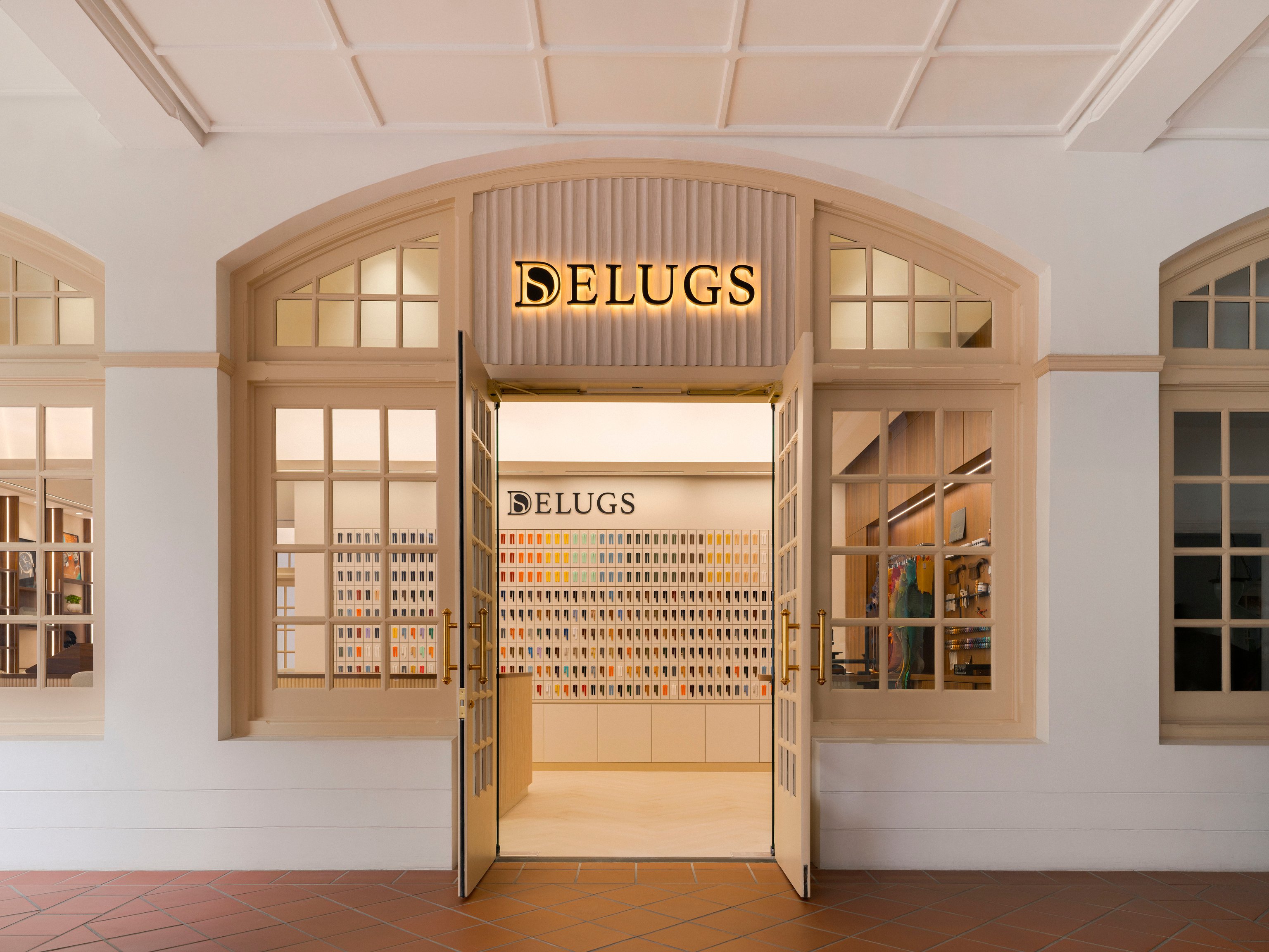 Storefront with open doors revealing brightly lit interior and shelves full of colorful products under the sign "DELUGS."